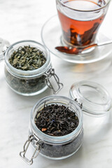 Jars with different sorts of dry tea leaves on table