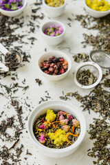 Bowls with different sorts of dry tea leaves on table