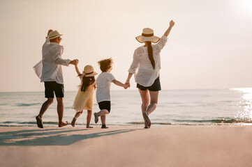 Asian family vacation holiday, Happy family running on the beach in the evening. Back view of a...