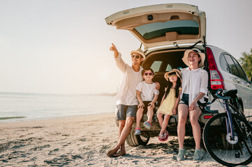 Happy asian family enjoying beach trip with their favorite car. Parents and children are traveling...
