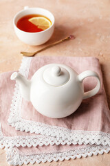 Teapot and cup of tea on color background