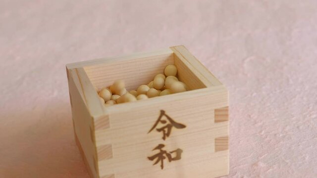 令和と書かれた枡に注がれる大豆　こぼれる