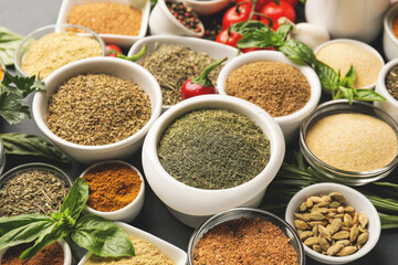 Bowls with different spices and herbs on dark background, closeup