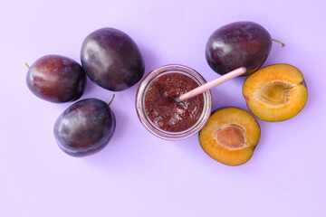 Glass jar with delicious homemade plum jam on color background