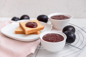 Bowls with delicious homemade plum jam on light background