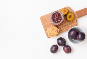Glass jar with delicious homemade plum jam on white background