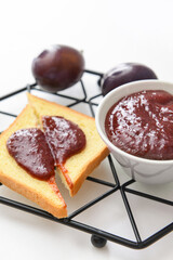 Composition with delicious homemade plum jam on white background
