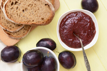 Bowl with delicious homemade plum jam on wooden background