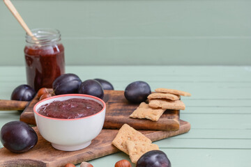 Bowl with delicious homemade plum jam on wooden background