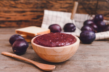Bowl with delicious homemade plum jam on wooden background