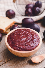 Bowl with delicious homemade plum jam on wooden background