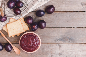 Bowl with delicious homemade plum jam on wooden background