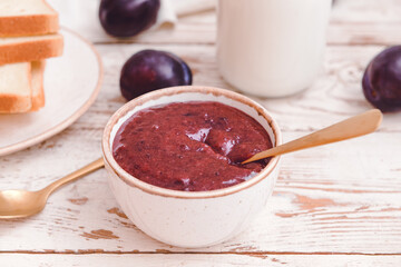 Bowl with delicious homemade plum jam on wooden background