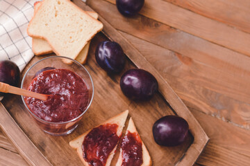 Composition with delicious homemade plum jam on wooden background