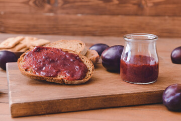 Composition with delicious homemade plum jam on wooden background