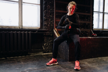 Girl fighter bandages her hands before training in the gym. Red Neon Light