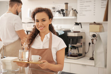 Young barista with cup of hot espresso in cafe