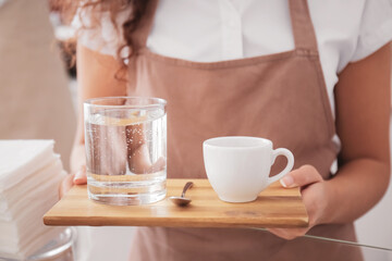 Young barista with cup of hot espresso in cafe, closeup