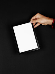 Photo frame in hands on a black background. Preparation for text, mockup, copy space.