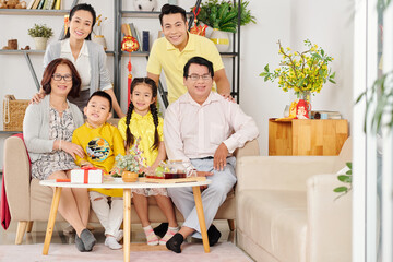 Smiling children, parents and grandparents gathered at home to celebrate Lunar New Year, decorations with best wishes in background