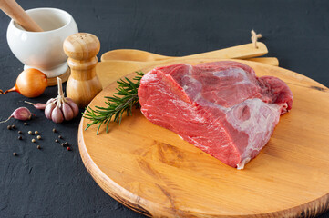 Raw whole beef sirloin on chopping board with herbs and spices