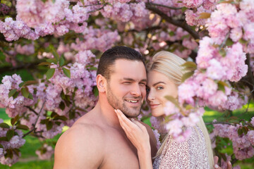 Young couple in love. Outdoor portrait of young lovers couple near sakura. Sensual couple in cherry sakura blossoms flowers.