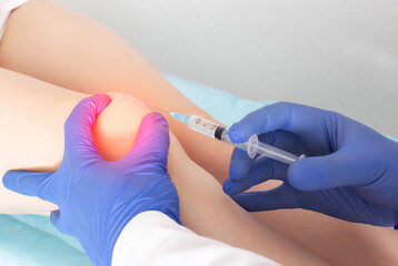 The doctor injects injections with hyaluronic acid into the knee joint of a patient who has pain...