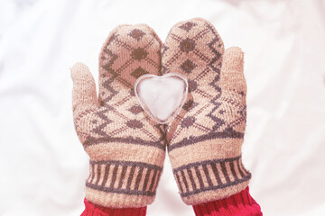 Ice Heart in hands in Winter Warm Gloves. Valentines Day and Love thematic concept photo.