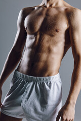 Fototapeta na wymiar sporty male bodybuilder with abs cubes on stomach gray background
