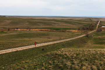 lone girl in red dress walking on the road in the countryside