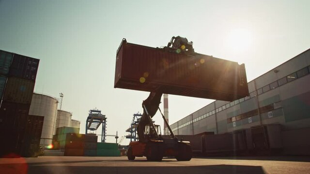 VFX Industrial Scene with Computer Generated Double Girder Gantry Cranes Working in the Background of a Container Handler Carrying a Large Shipping Container in a Shipyard Logistics Center Terminal.