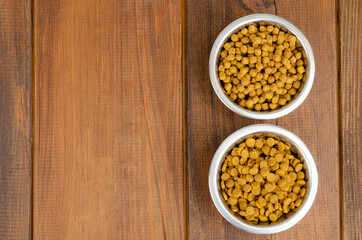 Dry cat food in metal bowl on wooden background. Studio Photo