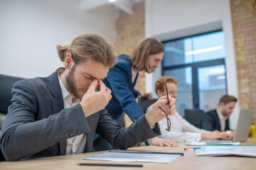 Obraz premium Tired man with closed eyes sitting in office