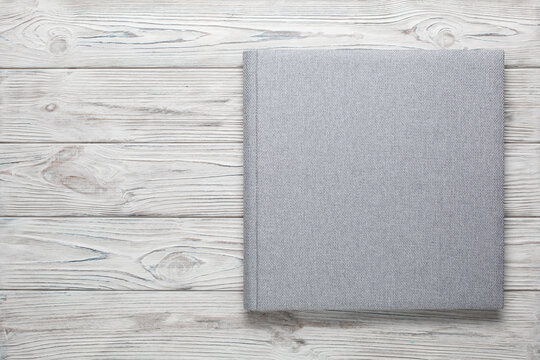 family photo book with grey fabric cover. stylish wedding photo album on wooden background with copy space for text. light photobook close up. family photoalbum  with beautiful texture cover isolated