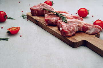 Raw t-bone steak on wooden cutting board on wooden table