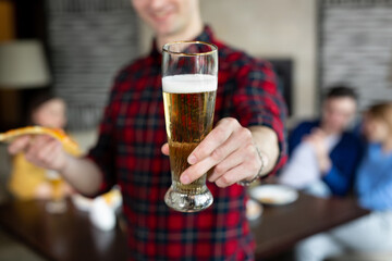Portrait of a young man holding pizza and beer in a pub