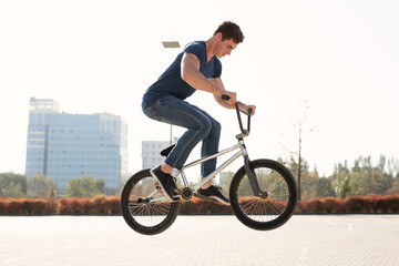 Street portrait of a bmx rider in a jump on the street in the background of the city landscape