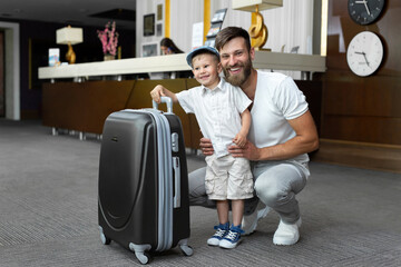 Father and son with a suitcase at the hotel reception