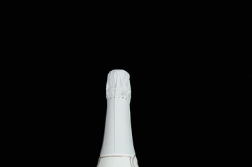 Neck of a bottle of champagne in white foil on a black background.