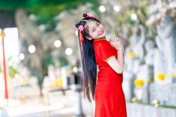 Portrait beautiful smiles Cute little Asian girl wearing red traditional Chinese cheongsam decoration for Chinese New Year Festival at Chinese shrine