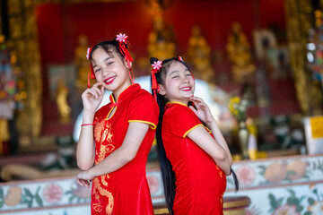 Portrait beautiful smiles Cute little Asian Two girl wearing red traditional Chinese cheongsam decoration for Chinese New Year Festival at Chinese shrine