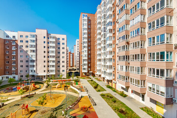 Top view of courtyard among new modern high-rise residential buildings in sunny summer day. Safety car-free place with children playgrounds among city living buildings