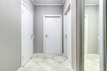 Empty gray hallway in contemporary living apartment without furniture and with closed doors
