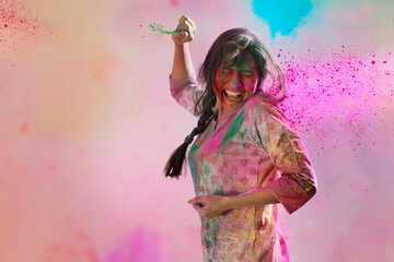 Woman with colors all around standing with her eyes closed in surprise and gulal in her hands on Holi	
