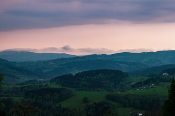 Paysage de montagne avec la forêt de tous les verts possibles, un ciel nuageux et bleu. La forêt est composée principalement de résineux, épicéas sapins et pins.