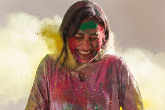 Woman Smiling Ecstatically While Playing With Colors On Holi	