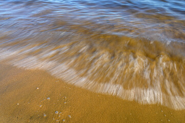 Waves on the seashore captured with a slow shutter speed. Natural abstract motion background.