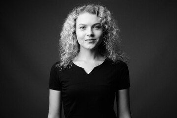 Fototapeta premium Young beautiful woman with curly blond hair against gray background