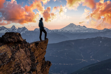 Adventurous man is standing on top of the mountain and enjoying the beautiful view. Taken on top of Cheam Peak in Chilliwack, East of Vancouver, BC, Canada. Colorful Sunset Sky Art Render