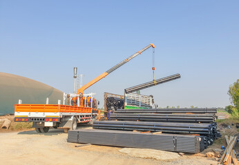 The crane lifts the steel structure off the truck.